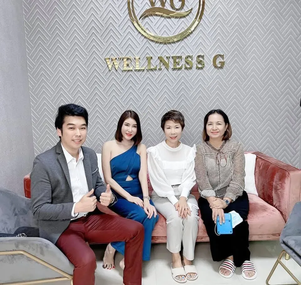 ทีมบริหาร Wellness G ถ่ายภาพหน้าป้ายโลโก้ WELLNESS G ของโรงงานรับผลิตอาหารเสริมและเครื่องสำอาง OEM